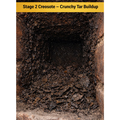 Stage 2 creosote in a chimney: crunchy tar buildup with darker brittle flakes along chimney walls.